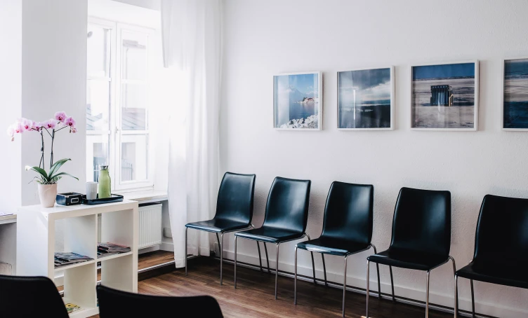 Wartebereich der Hauptpraxis mit Sitzreihe und Bildern an der Wand